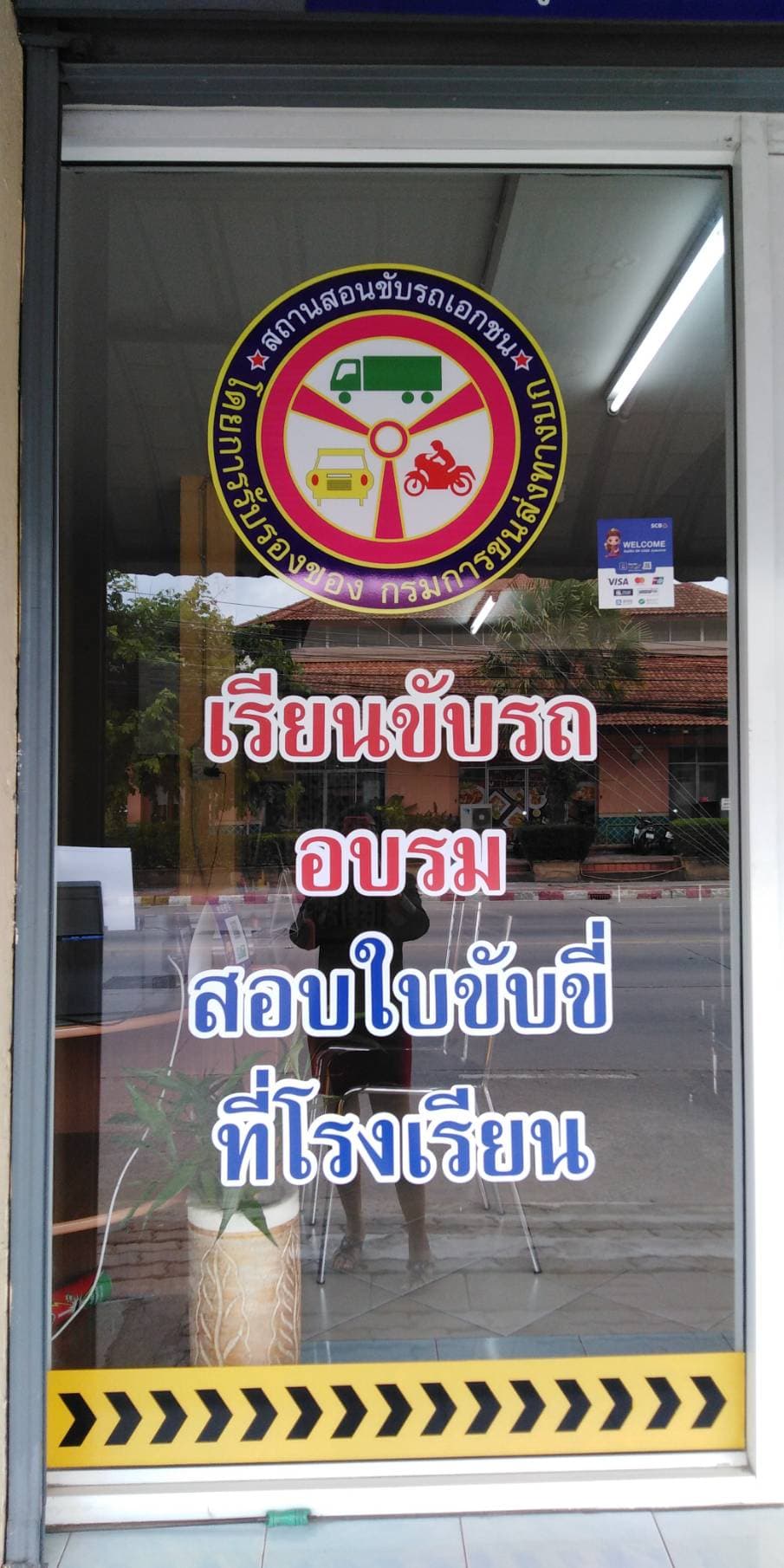 The accredited driving school seal from the Department of Land Transport, displayed on the Sky Pattaya office window